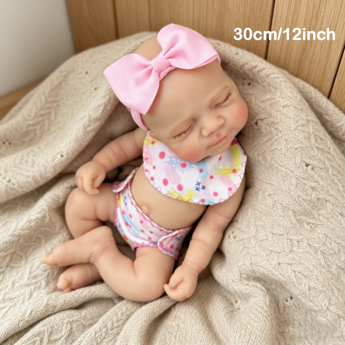 Bambola reborn Pascale in silicone da 30 cm addormentata con indosso un vestitino a fiori rosa