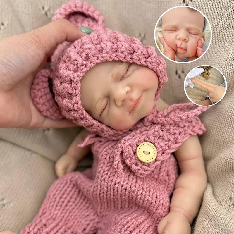 Bambola reborn Pascale da 30 cm in silicone realistica con occhi chiusi e salopette rossa lavorata a maglia