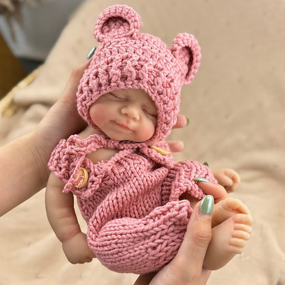 Bambola reborn Pascale da 30 cm in silicone realistica con occhi chiusi e salopette rossa lavorata a maglia