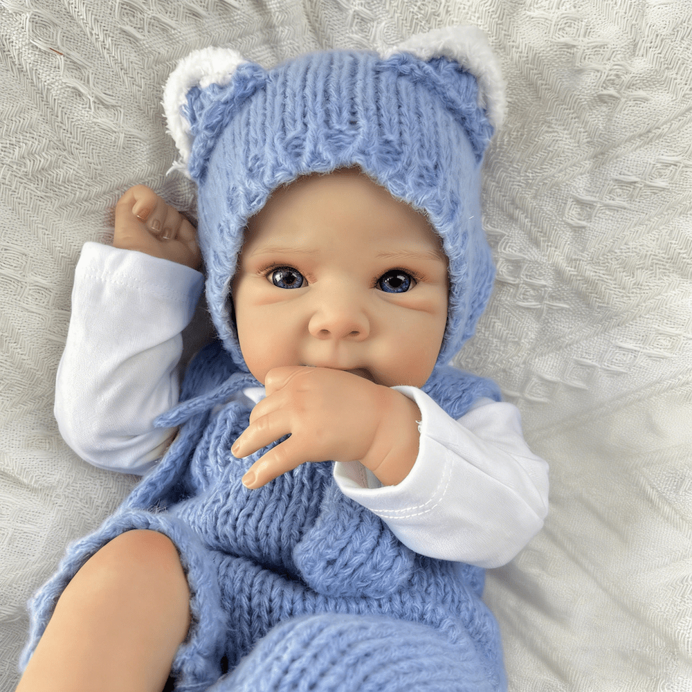 Bambola reborn Bettie da 45cm con occhi azzurri vestita con un body blu lavorato a maglia