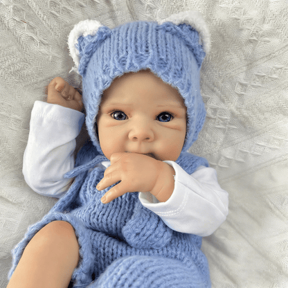Bambola reborn Bettie da 45cm con occhi azzurri vestita con un body blu lavorato a maglia