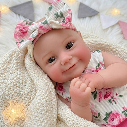 Bambola reborn Maddie in silicone estensibile da 30 cm con sorriso vestita con abitino floreale rosa