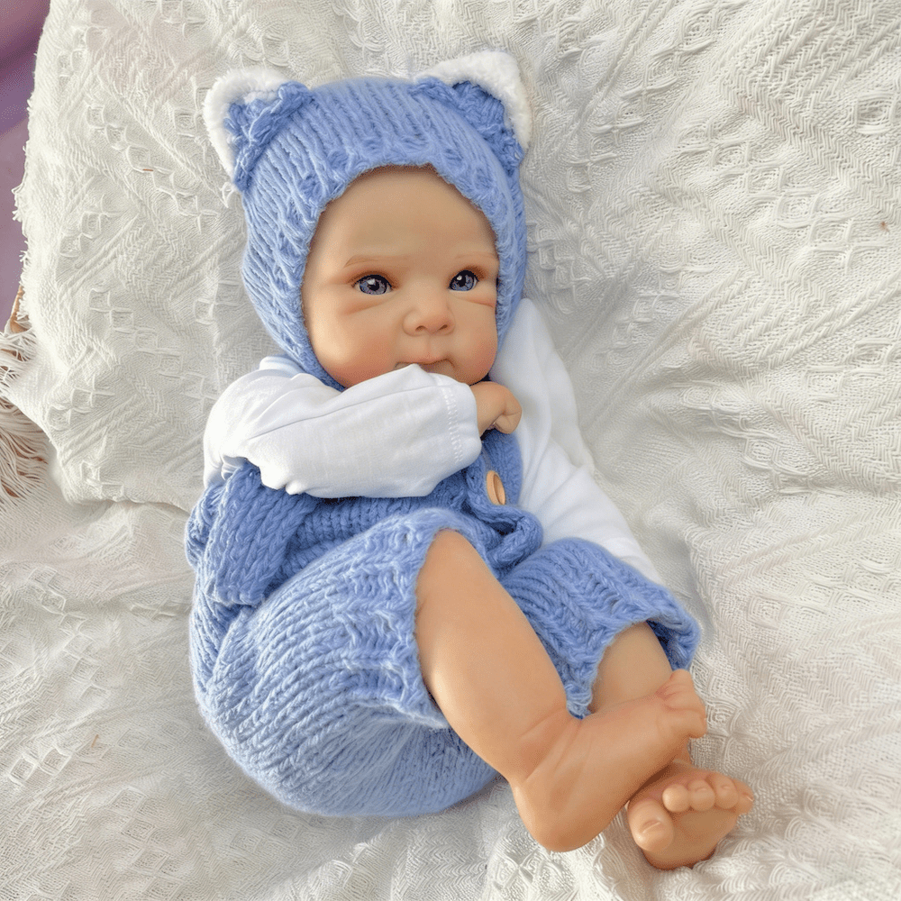 Bambola reborn Bettie da 45cm con occhi azzurri vestita con un body blu lavorato a maglia
