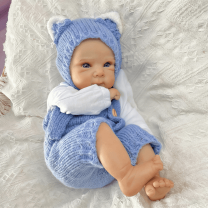 Bambola reborn Bettie da 45cm con occhi azzurri vestita con un body blu lavorato a maglia