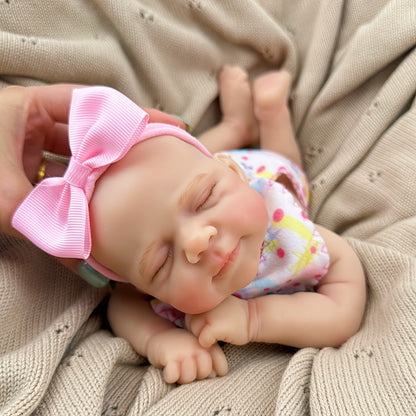 Bambola reborn Pascale in silicone da 30 cm addormentata con indosso un vestitino a fiori rosa