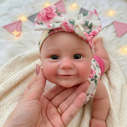 Bambola reborn Maddie in silicone estensibile da 30 cm con sorriso vestita con abitino floreale rosa