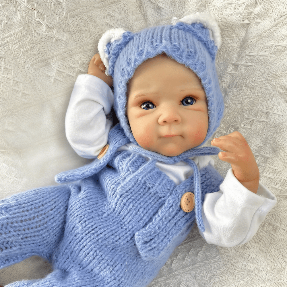 Bambola reborn Bettie da 45cm con occhi azzurri vestita con un body blu lavorato a maglia