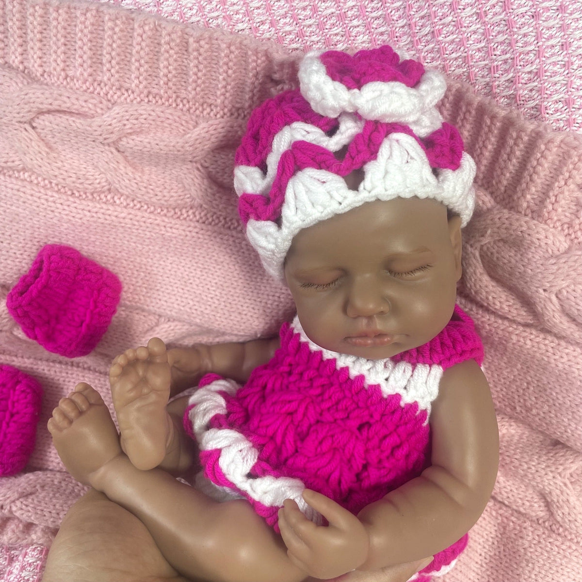 Bambola reborn Loulou in silicone 30cm realistica con pelle scura vestita con un maglione mentre dorme