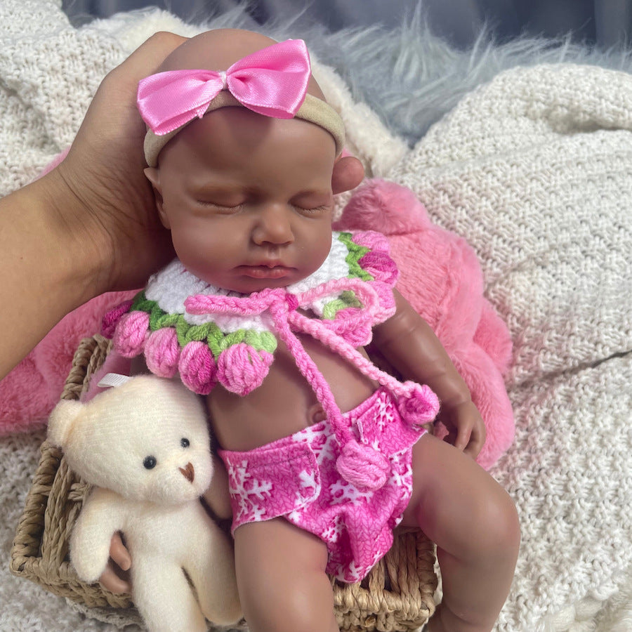 Bambola reborn Loulou in silicone realistica alta 30cm con pelle scura e vestiti rosa vestita da bambina addormentata