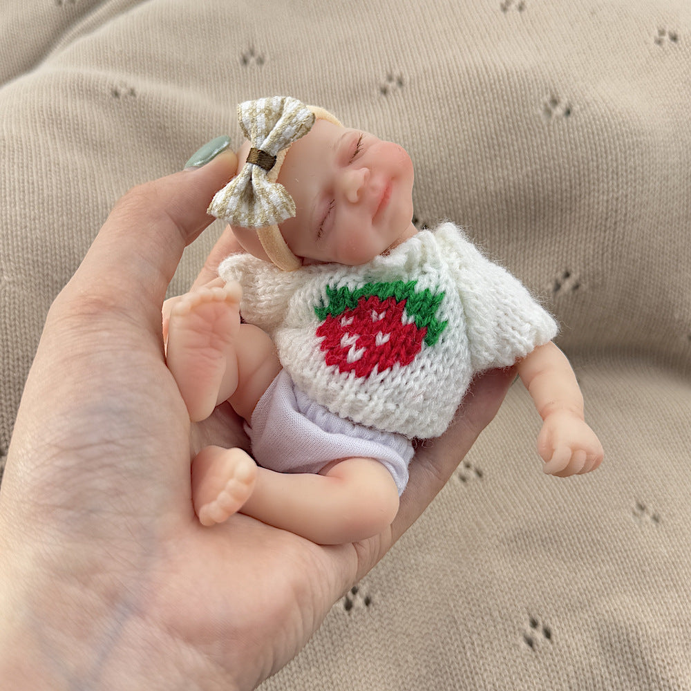 Bambola reborn Pascale in silicone da 15 cm con occhi chiusi e maglione bianco a fragole