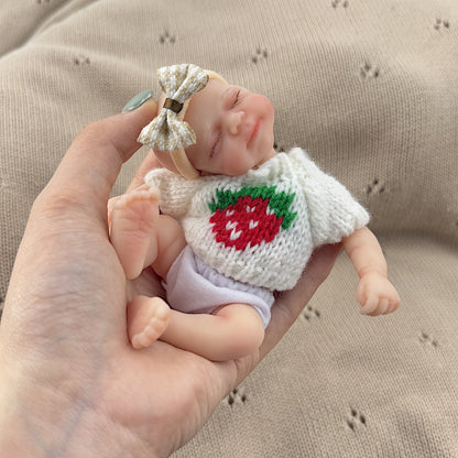 Bambola reborn Pascale in silicone da 15 cm con occhi chiusi e maglione bianco a fragole