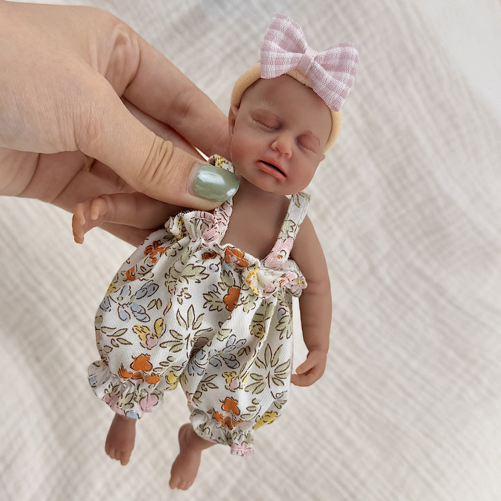 Bambola reborn Loulou Mini in silicone da 15 cm con pelle scura e vestiti floreali