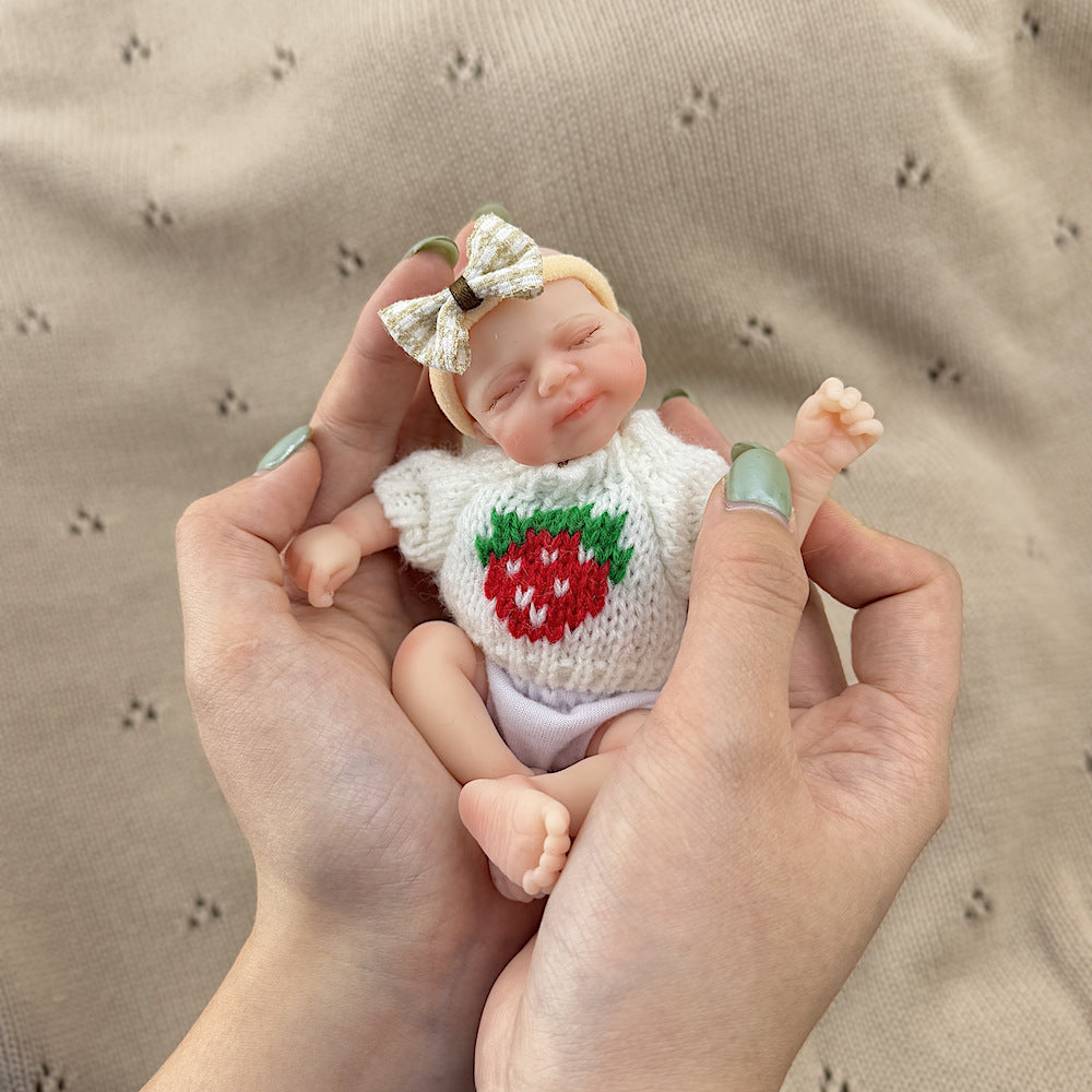 Bambola reborn Pascale in silicone da 15 cm con occhi chiusi e maglione bianco a fragole