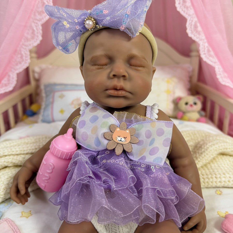 Bambola reborn Loulou in silicone 30cm realistica con pelle scura e vestito viola addormentata