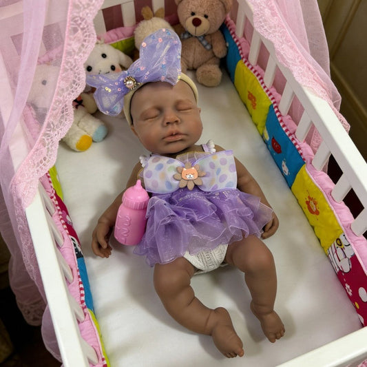 Bambola reborn Loulou in silicone 30cm realistica con pelle scura e vestito viola addormentata