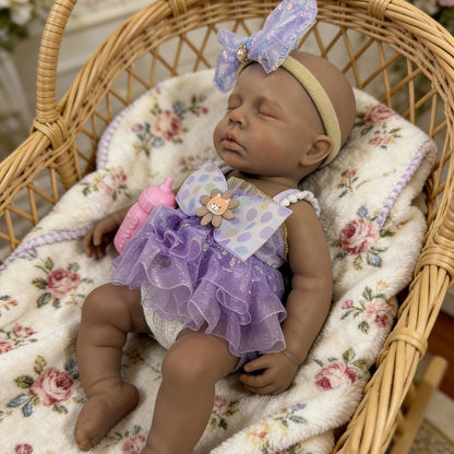 Bambola reborn Loulou in silicone 30cm realistica con pelle scura e vestito viola addormentata