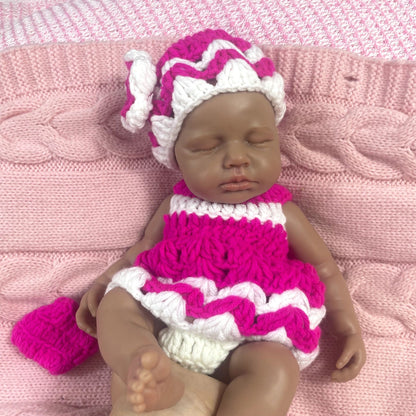 Bambola reborn Loulou in silicone 30cm realistica con pelle scura vestita con un maglione mentre dorme
