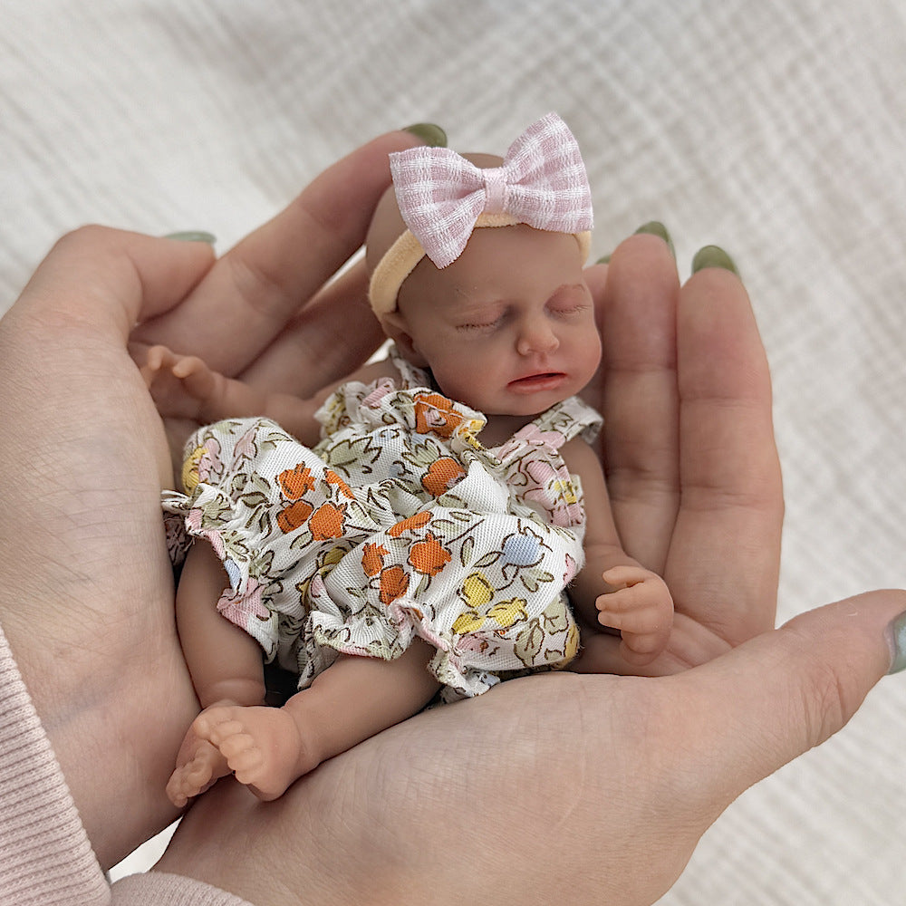 Bambola reborn Loulou Mini in silicone da 15 cm con pelle scura e vestiti floreali