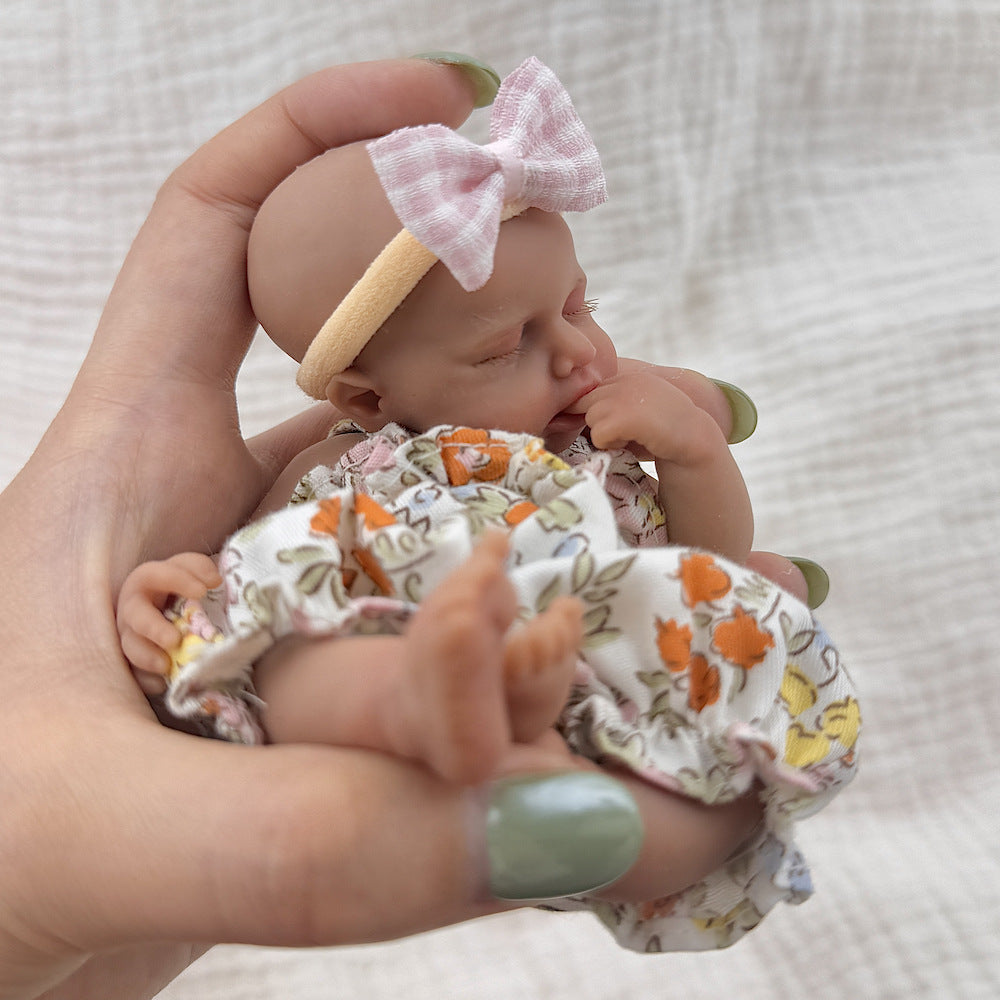 Bambola reborn Loulou Mini in silicone da 15 cm con pelle scura e vestiti floreali