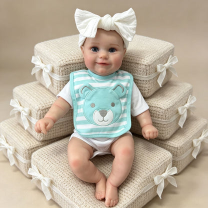 Bambola Reborn femminile Maddie da 50 cm realistica con occhi aperti sorriso e bavaglino a righe blu