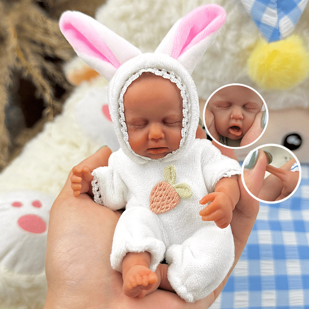 Bambola reborn Loulou Mini in silicone da 15 cm con pelle scura vestita da coniglio bianco