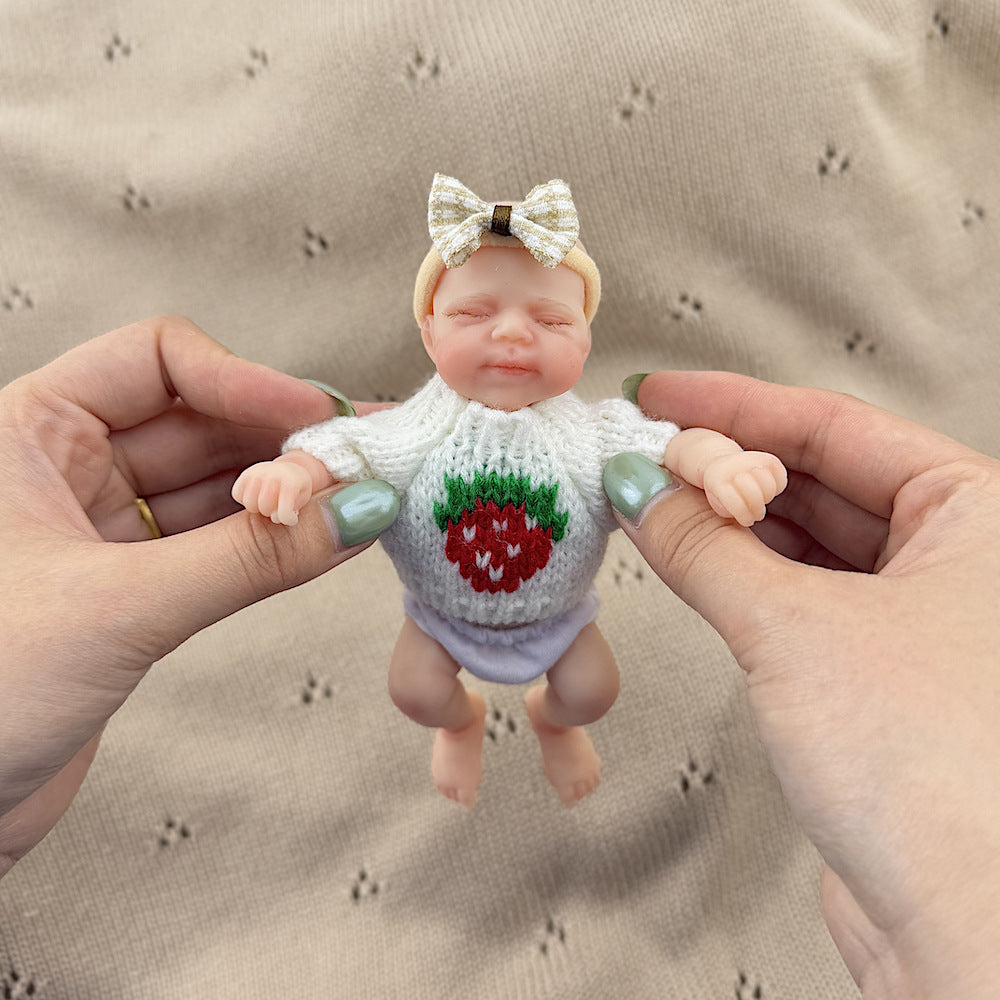 Bambola reborn Pascale in silicone da 15 cm con occhi chiusi e maglione bianco a fragole