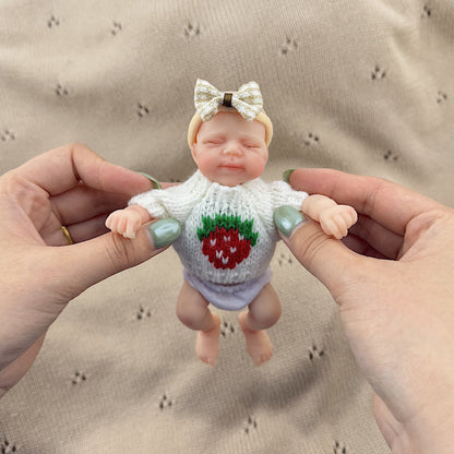 Bambola reborn Pascale in silicone da 15 cm con occhi chiusi e maglione bianco a fragole