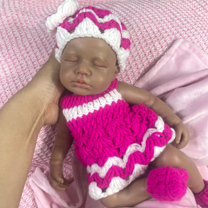 Bambola reborn Loulou in silicone 30cm realistica con pelle scura vestita con un maglione mentre dorme