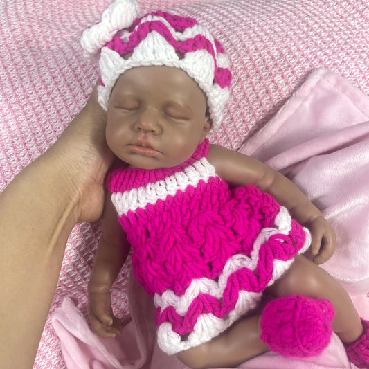 Bambola reborn Loulou in silicone 30cm realistica con pelle scura vestita con un maglione mentre dorme