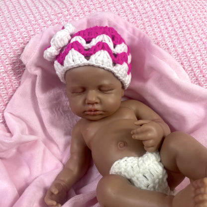 Bambola reborn Loulou in silicone 30cm realistica con pelle scura vestita con un maglione mentre dorme