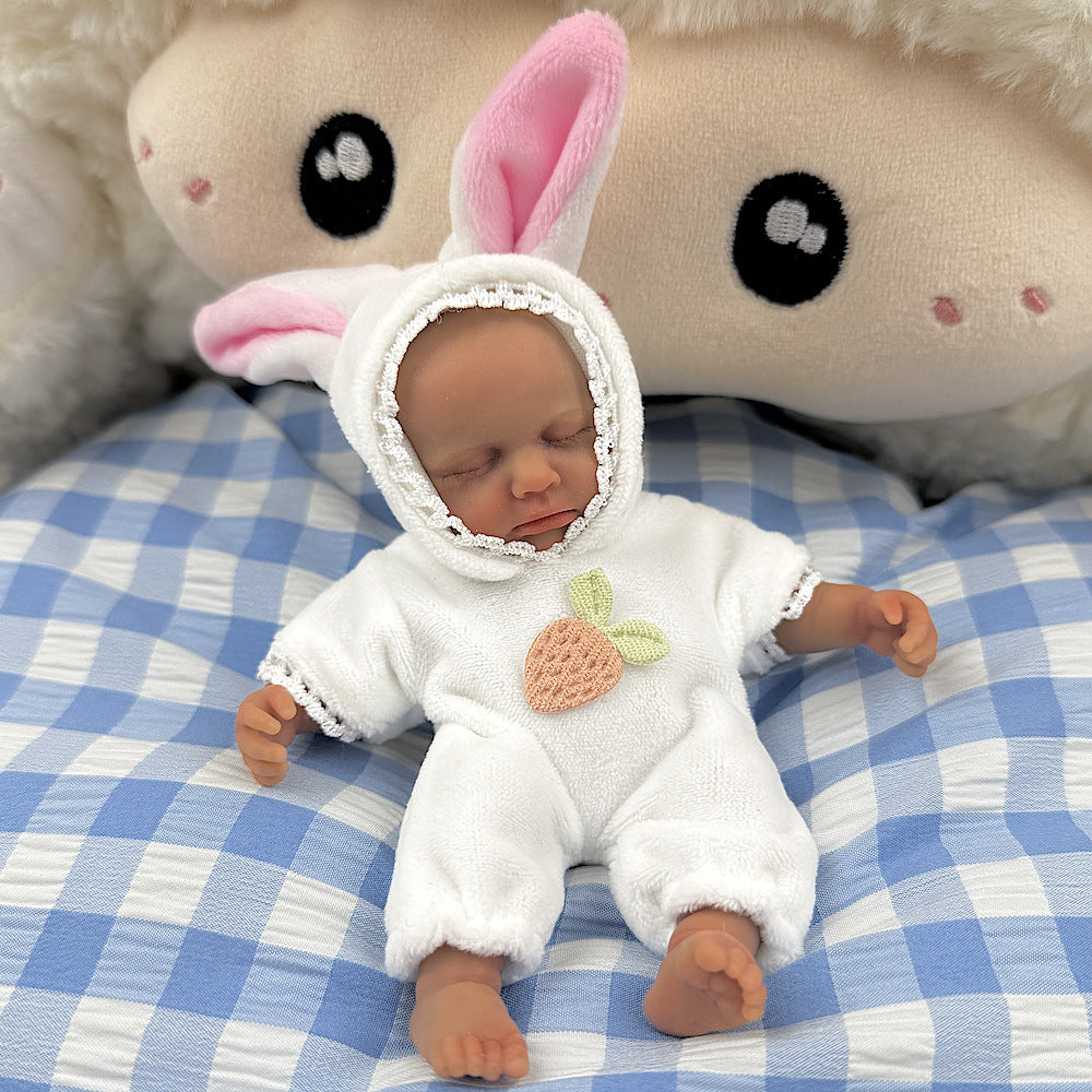 Bambola reborn Loulou Mini in silicone da 15 cm con pelle scura vestita da coniglio bianco