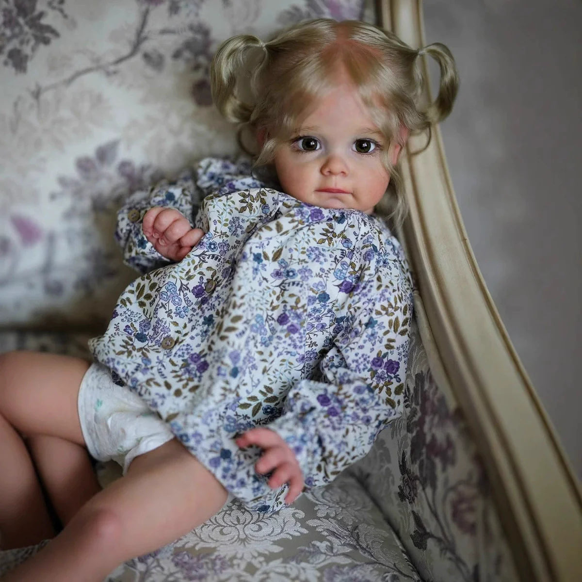 Bambola Reborn Maggie con Capelli Biondi e Occhi Aperti da 60 cm in Abiti Floreali
