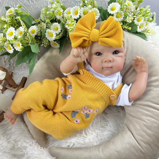 Bambina reborn Bettie da 48 cm con occhi azzurri realistici e corpo in vinile vestita con un abito giallo lavorato a maglia