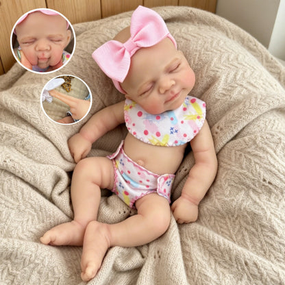 Bambola reborn Pascale in silicone da 30 cm addormentata con indosso un vestitino a fiori rosa