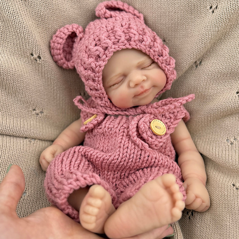 Bambola reborn Pascale da 30 cm in silicone realistica con occhi chiusi e salopette rossa lavorata a maglia