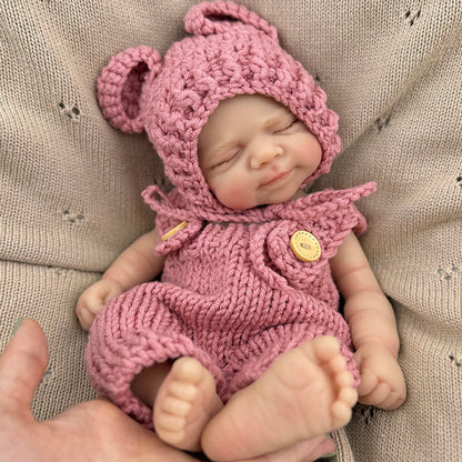 Bambola reborn Pascale da 30 cm in silicone realistica con occhi chiusi e salopette rossa lavorata a maglia