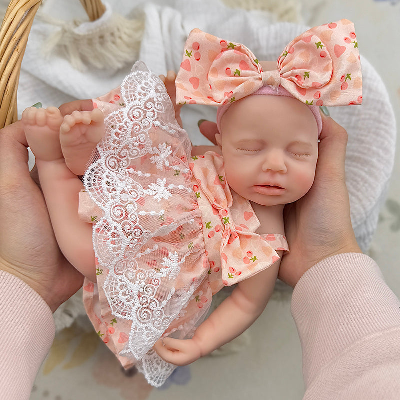 Bambola Reborn femmina Loulou da 30 cm in silicone pieno (occhi chiusi) con vestitino in pizzo a fantasia di ciliegie