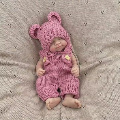 Bambola reborn Pascale da 30 cm in silicone realistica con occhi chiusi e salopette rossa lavorata a maglia