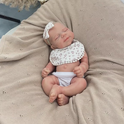 Bambola Reborn Pascale da 45 cm in silicone pieno flessibile dormiente con bavaglino a fiori