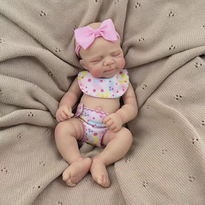 Bambola reborn Pascale in silicone da 30 cm addormentata con indosso un vestitino a fiori rosa